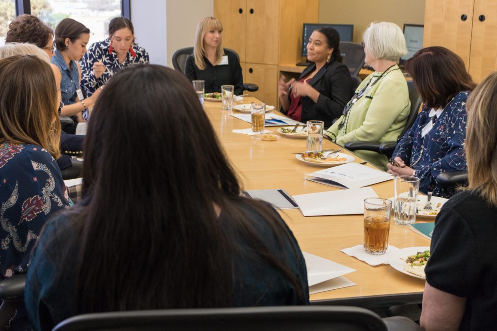 A group of women sit around a conference table having lunch
