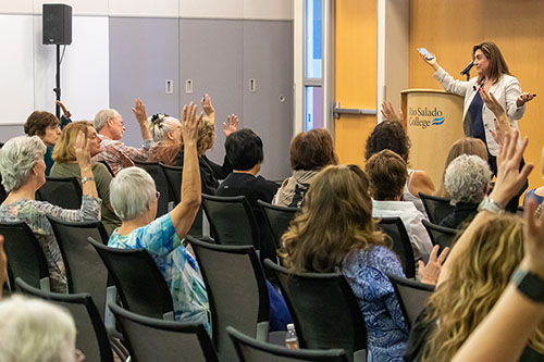 People in an audience raise their hands