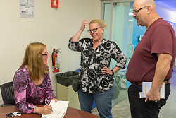 Two people standing talk to Karen Crouse who is seated at a table