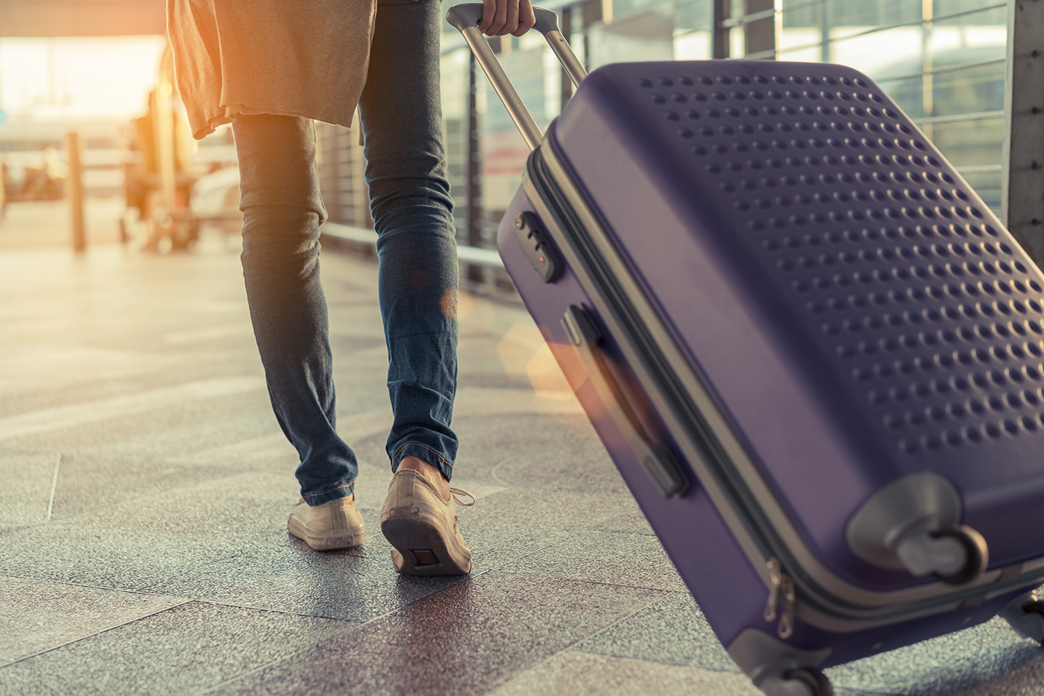 A woman walking in an airport pulling a carry-on luggage behind her